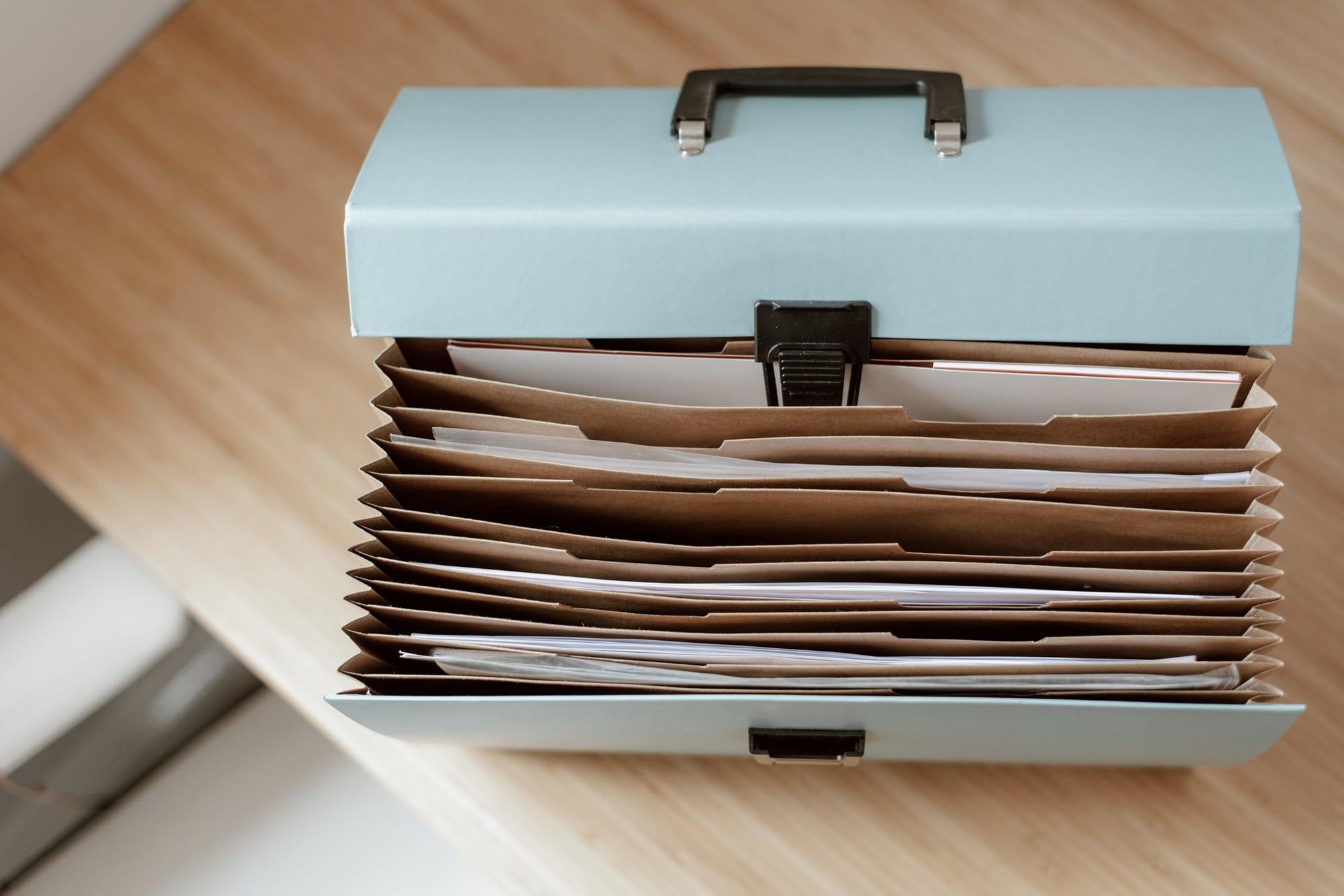 An open document case with sorted paper folders on a wooden table